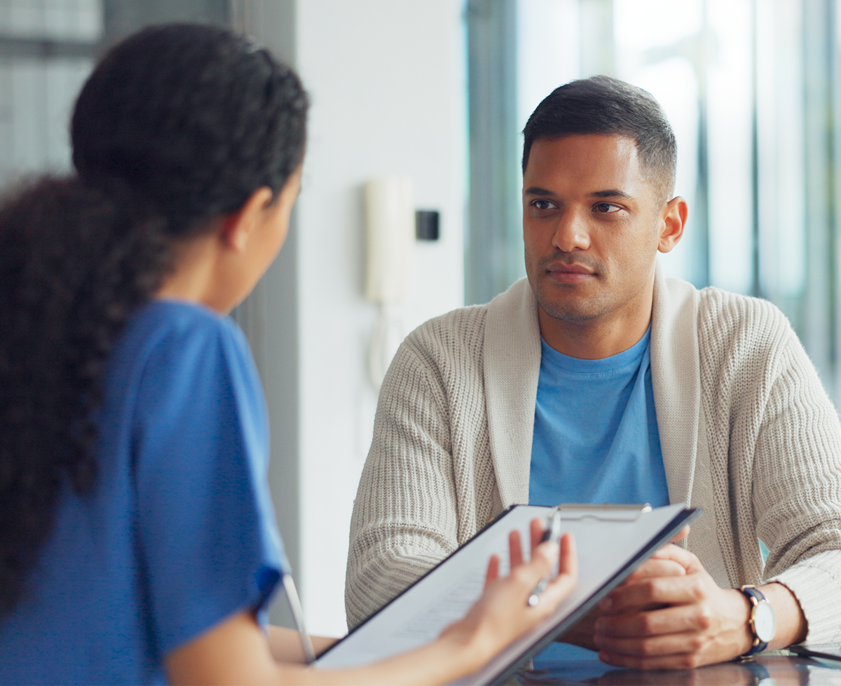 Man speaking with a nurse at a table.