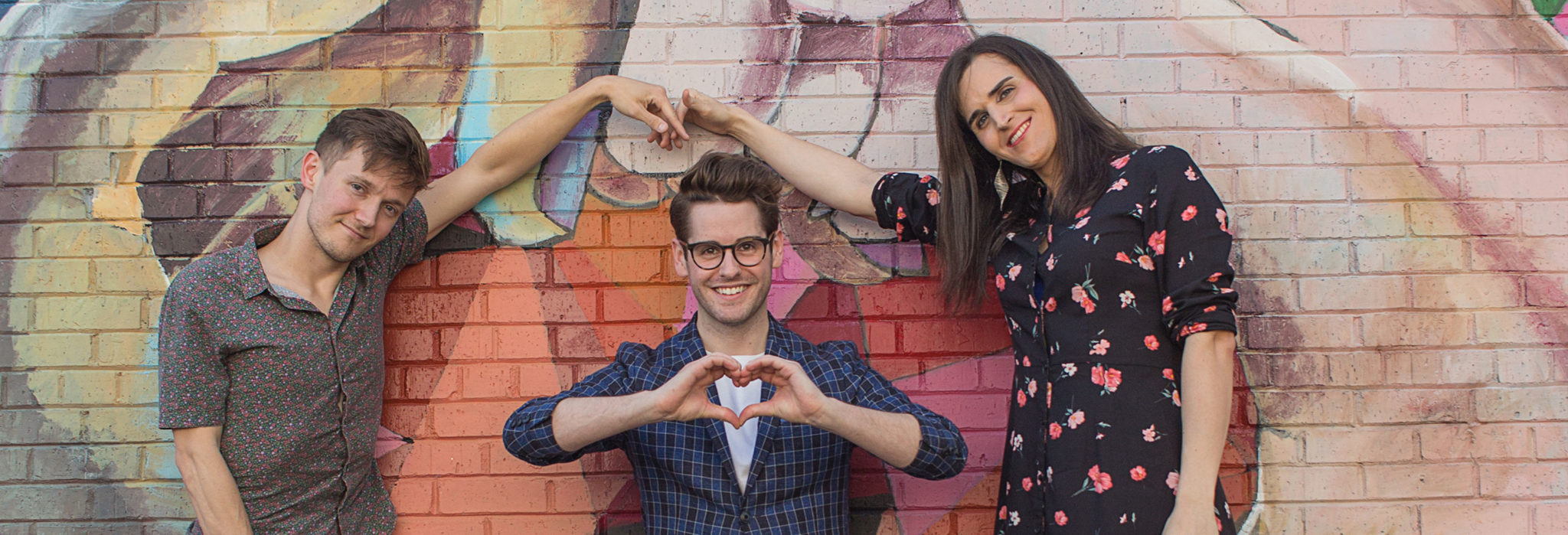 Group of white young LGBTQ people outside a color mural