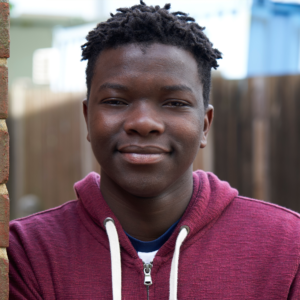 Photo of a yound, smiling black man in maroon zip up hoodie