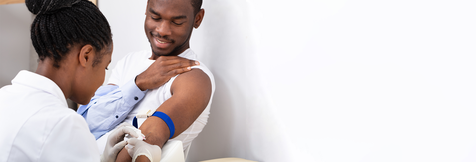 black female nurse performing a blood draw on black male patient