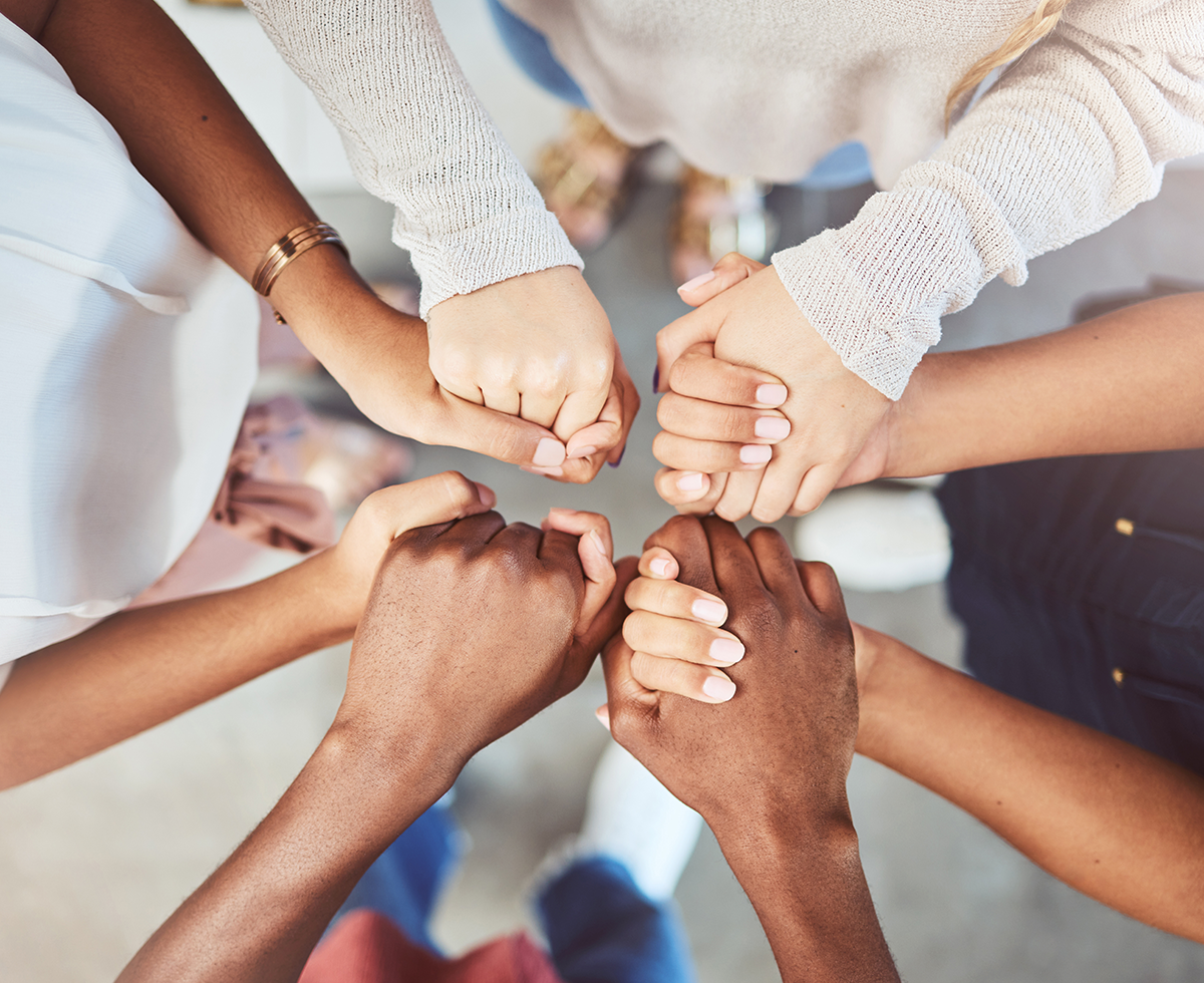 Close up image of group of hands holding each other in a circle.