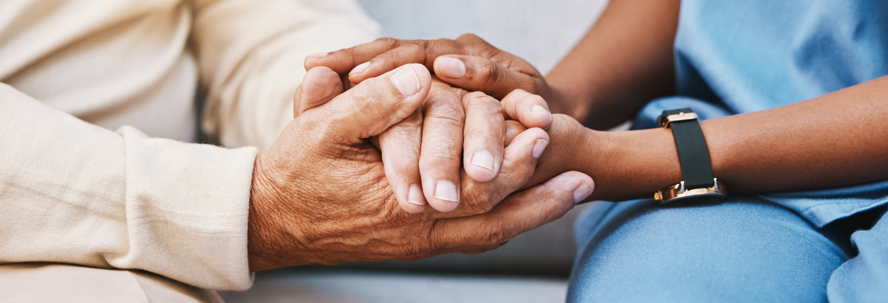 Black nurse holding hands with a Caucasian patient
